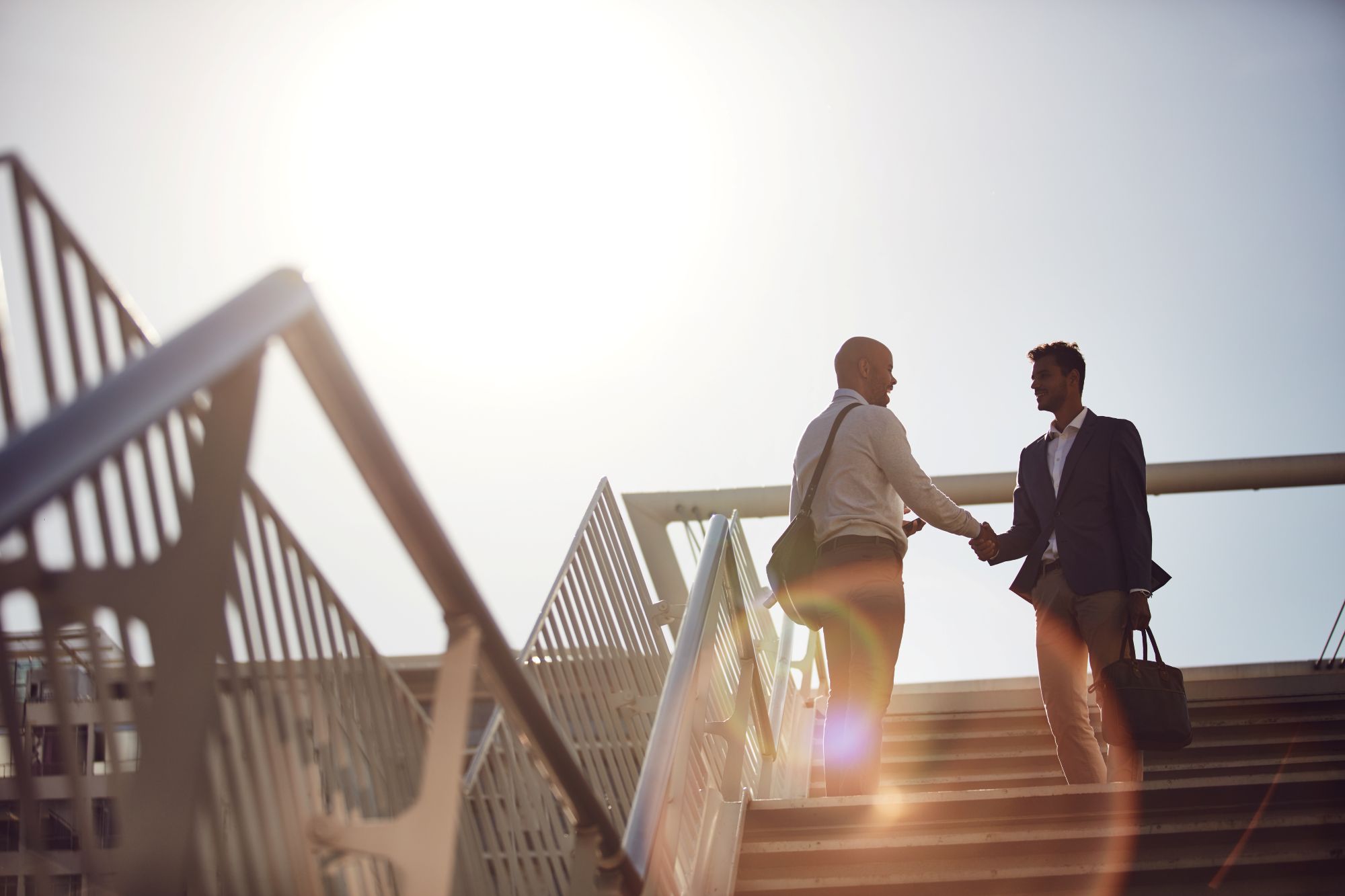 Two men in suits shake hands on a stair going up. Perhaps one is a breakaway advisor who has found the right independent platform at Sovereign Advisor Solutions