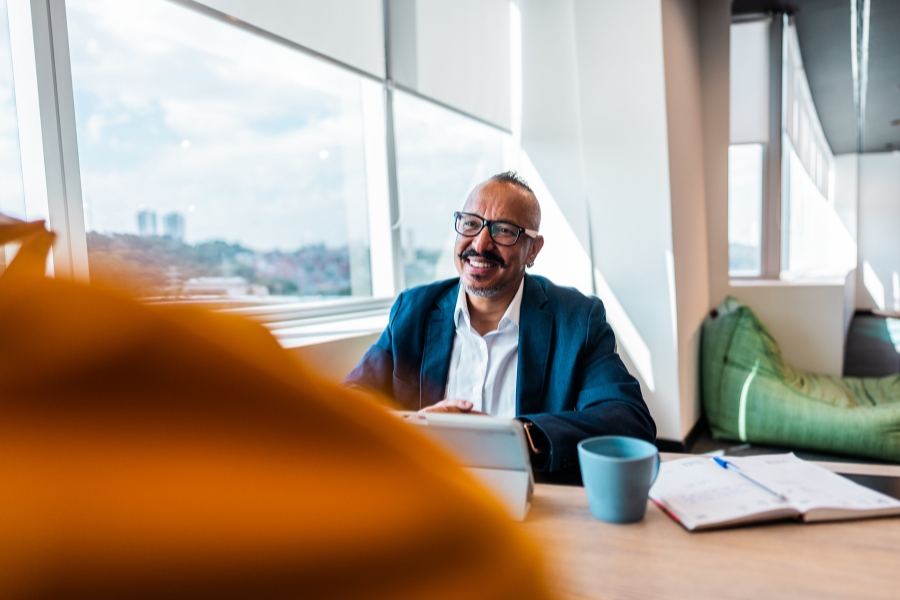 A middle aged man in a sunny office smiles across a desk - maybe at a client - he has more time for his clients because Sovereign handles the tech and service for his practice.