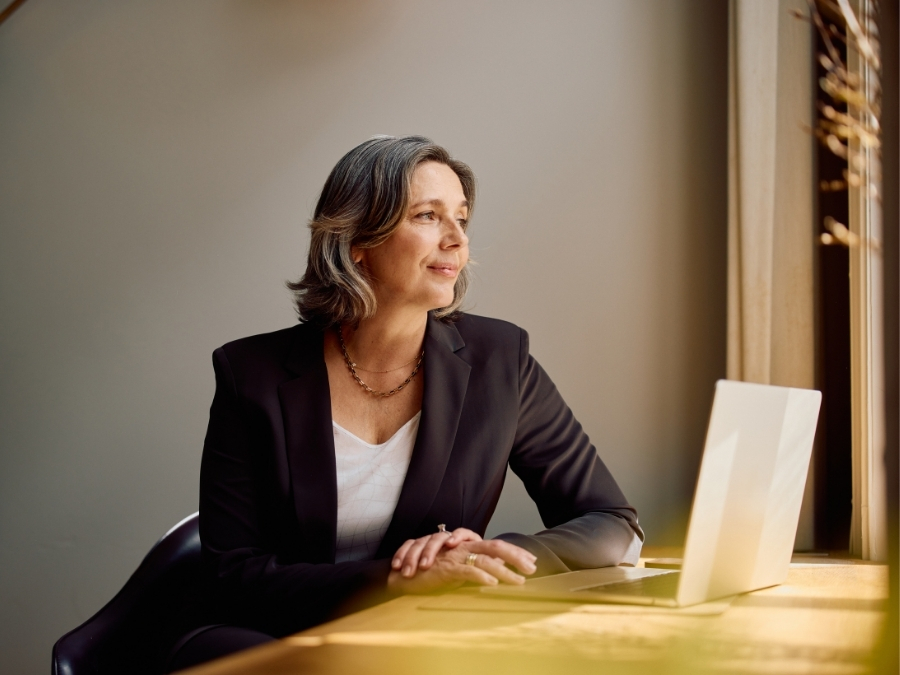 A woman in a suit, maybe an RIA, smiles calmly over her laptop - maybe because Sovereign Advisor Solutions makes the technology of independence so simple.